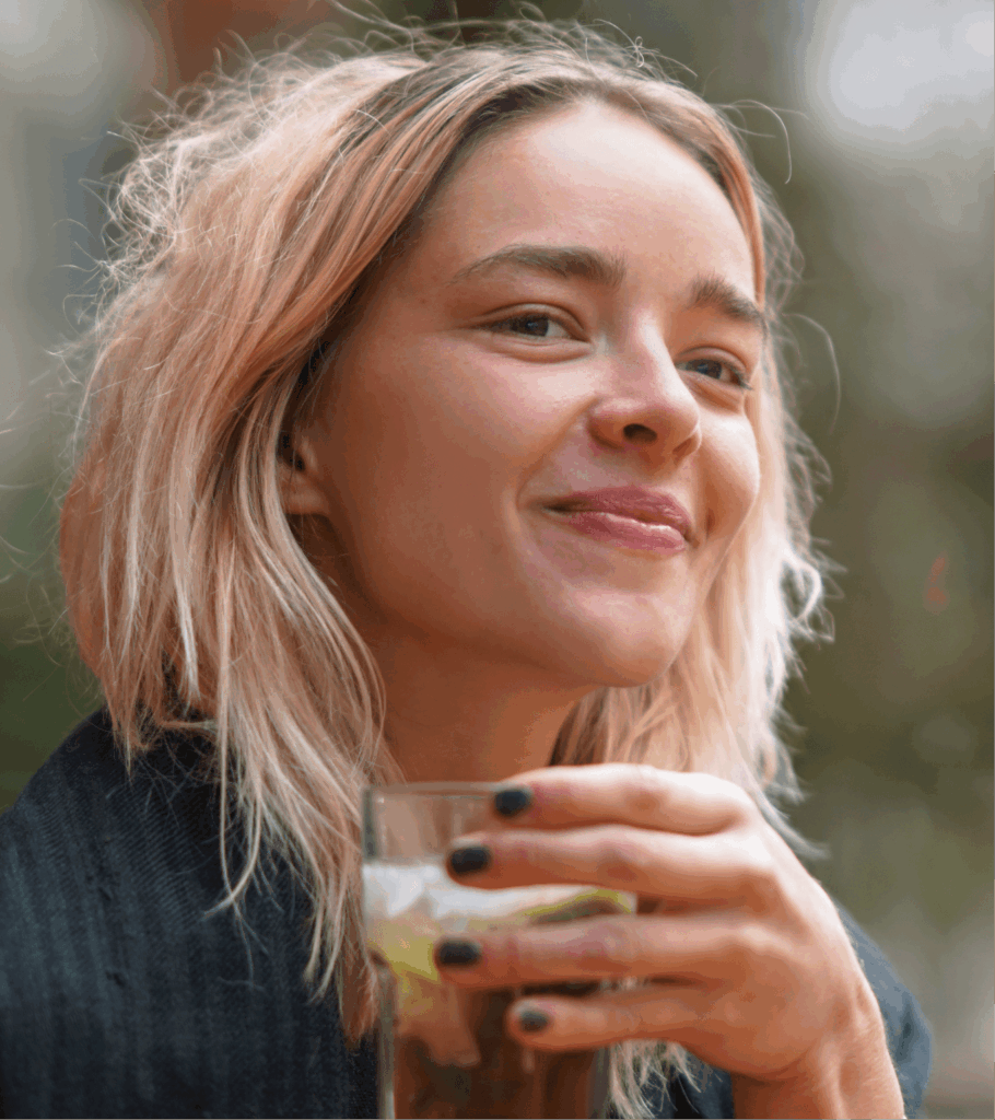Foto einer blonden Frau, die Bio Eistee im Glas trinkt