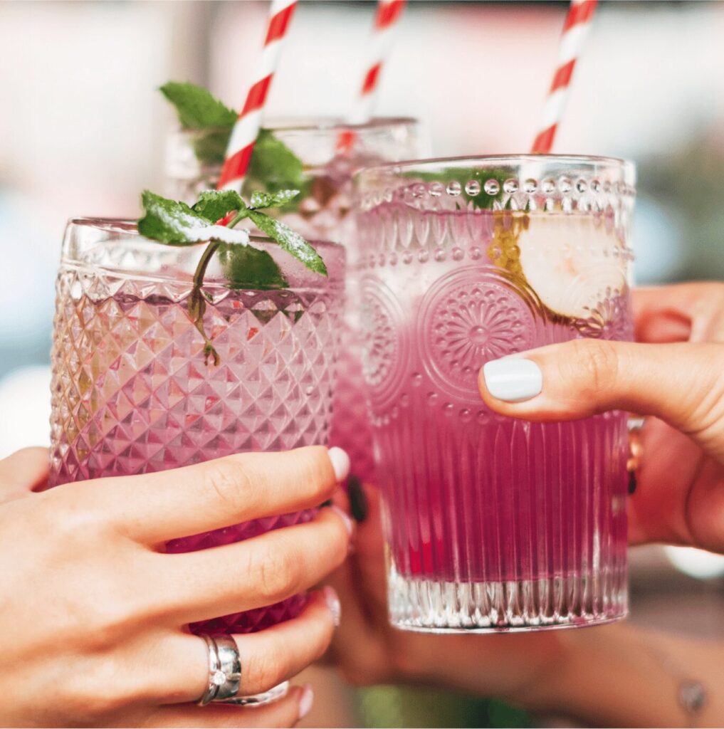 HÃ¶llinger Sirupe im Glas beim AnstoÃŸen mit Minze und Strohhalmen serviert.