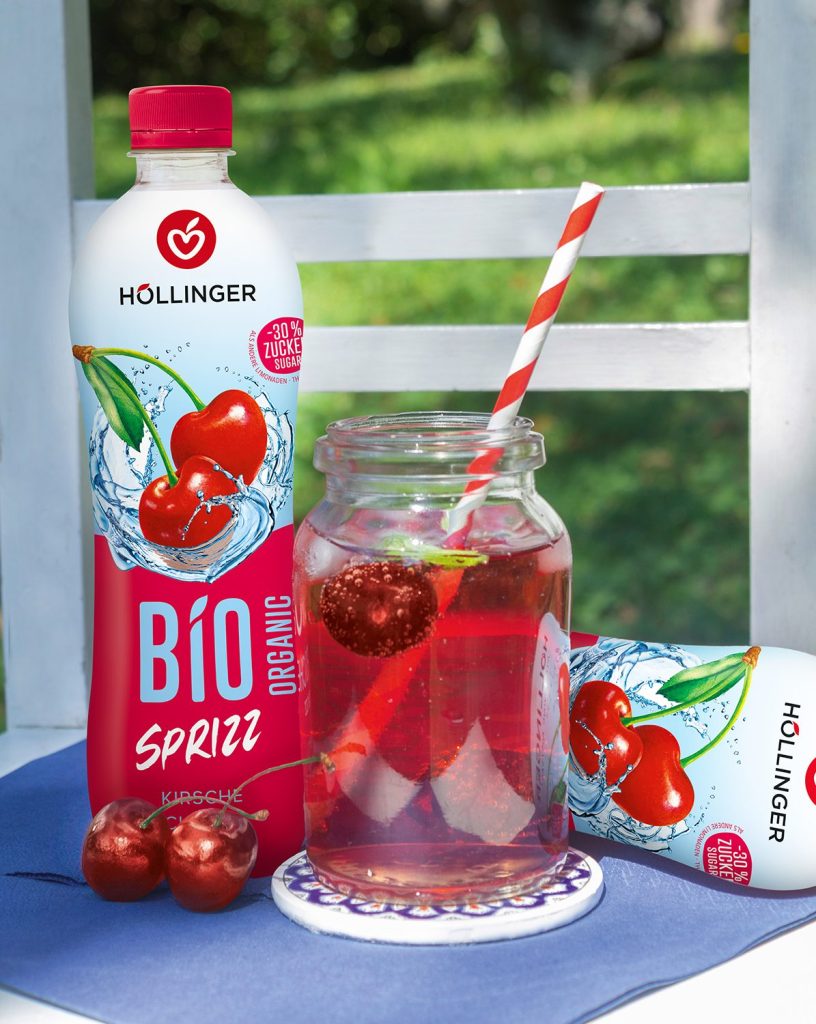 Kirsch Sprizz im Glas mit PET Flasche im Hintergrund
